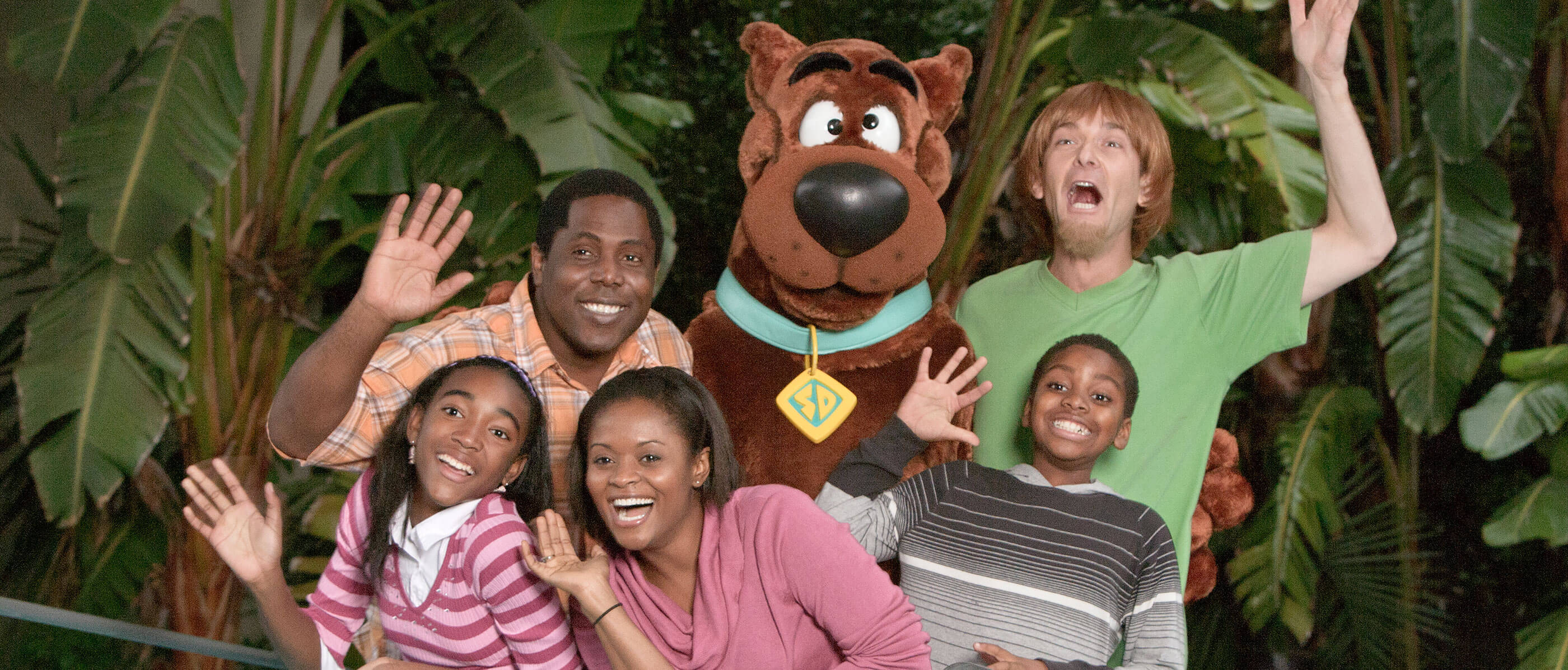 A family beside a stuffed Scooby Doo with trees behind them.