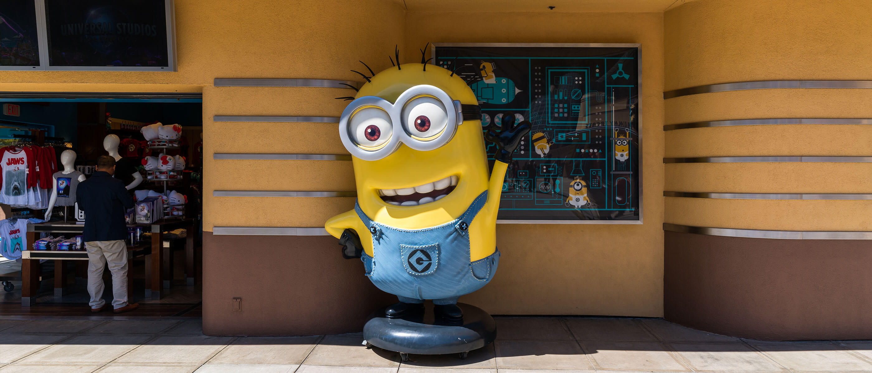 Statue of a minion in front of a store.