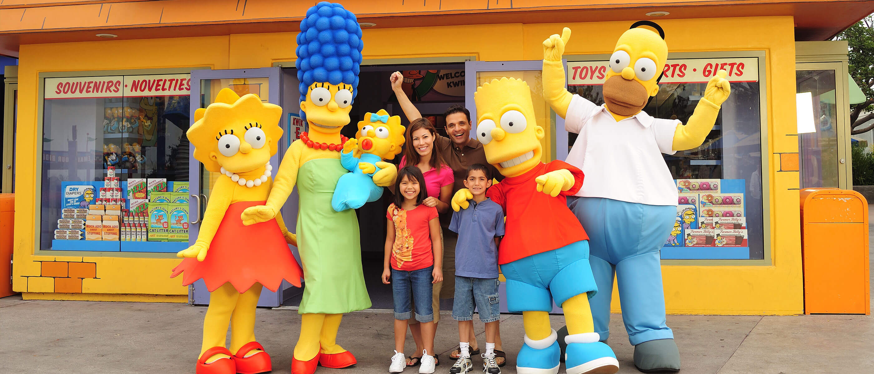 Family taking a picture with the Simpsons family in front of the Kwik-E-Mart entrance