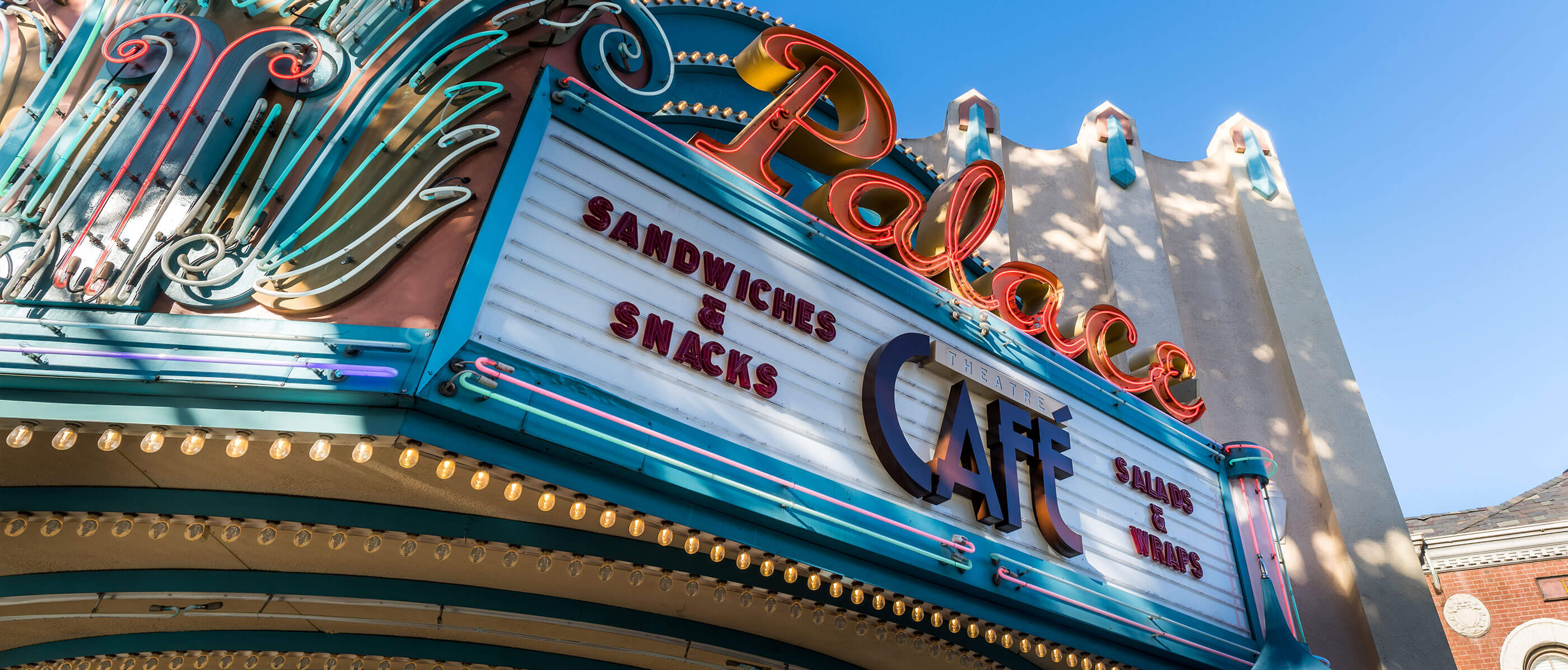 A Palace Cafe sign with writing saying sandwiches, snacks and salads and wraps.