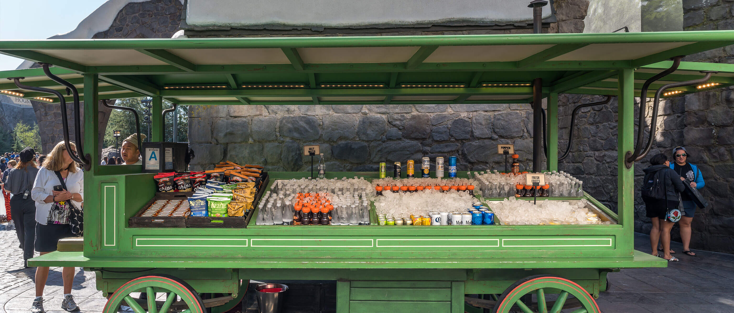 A green cart with food and beverages on it.