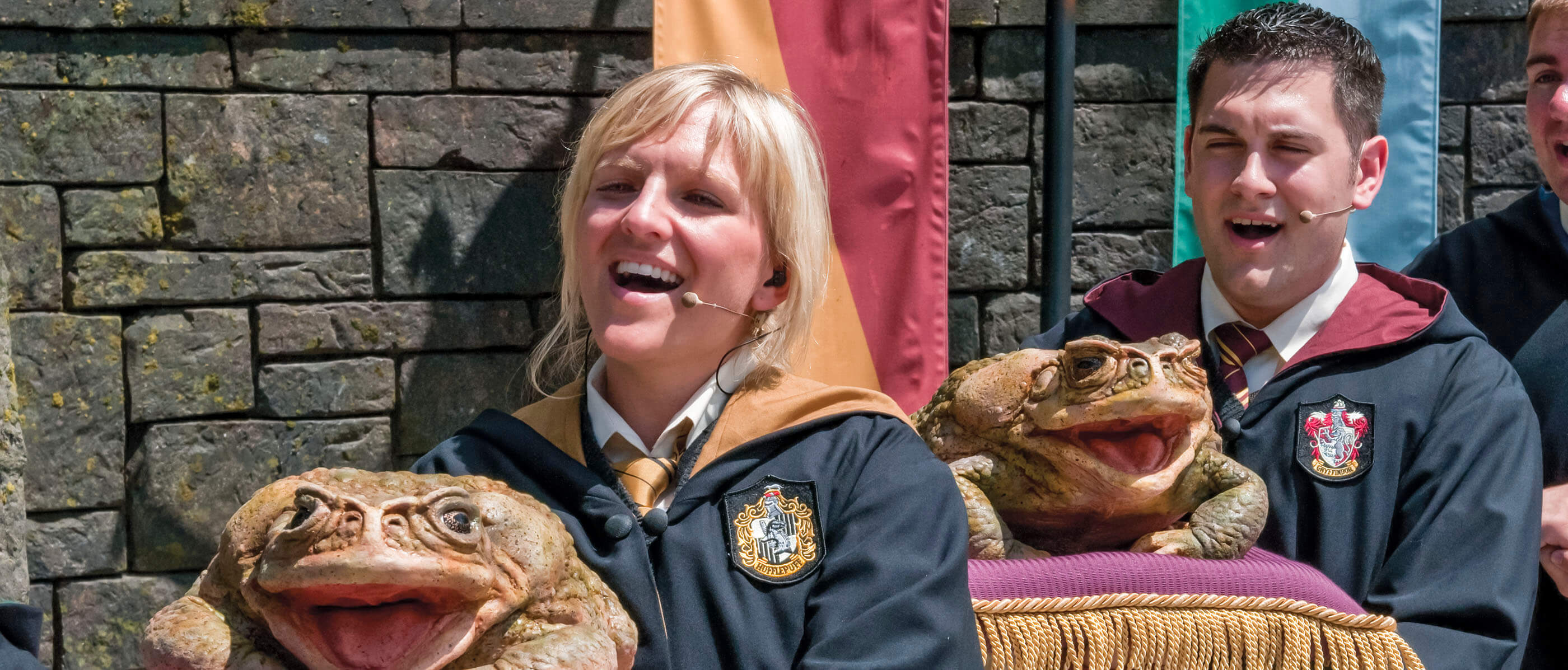 Two people singing with large frog props.