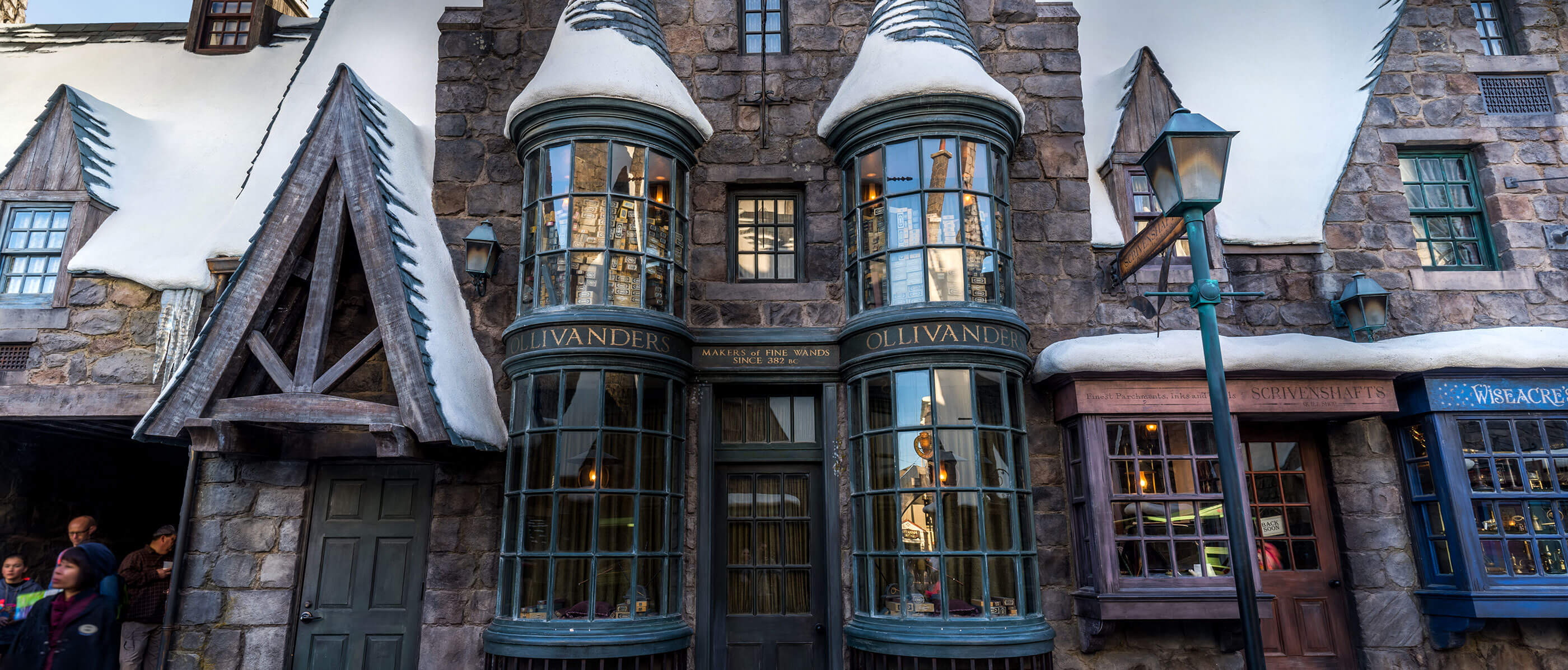 Outside of Ollivanders wand store with big windows and made of stone.