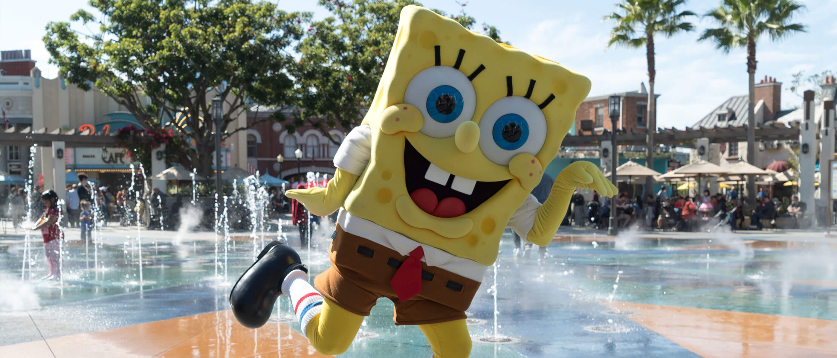 Someone in a Spongebob Squarepants costume dancing in a water fountain.