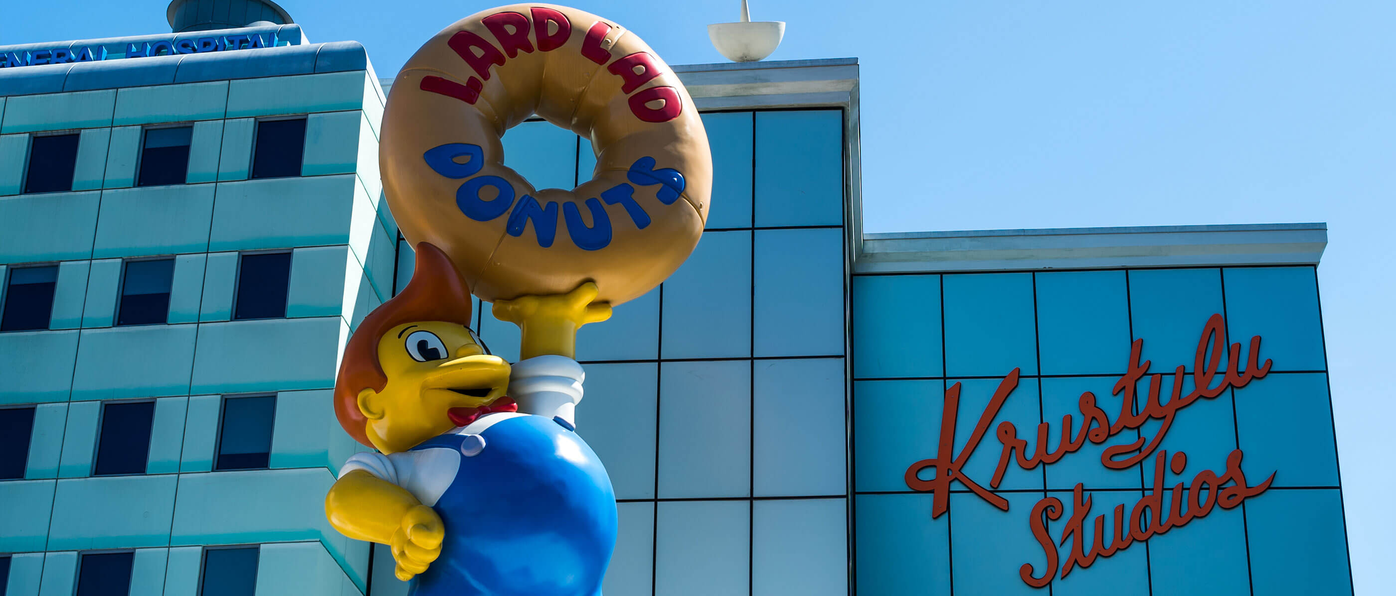Statue of a cartoon man holding a Lard Lad Donut.
