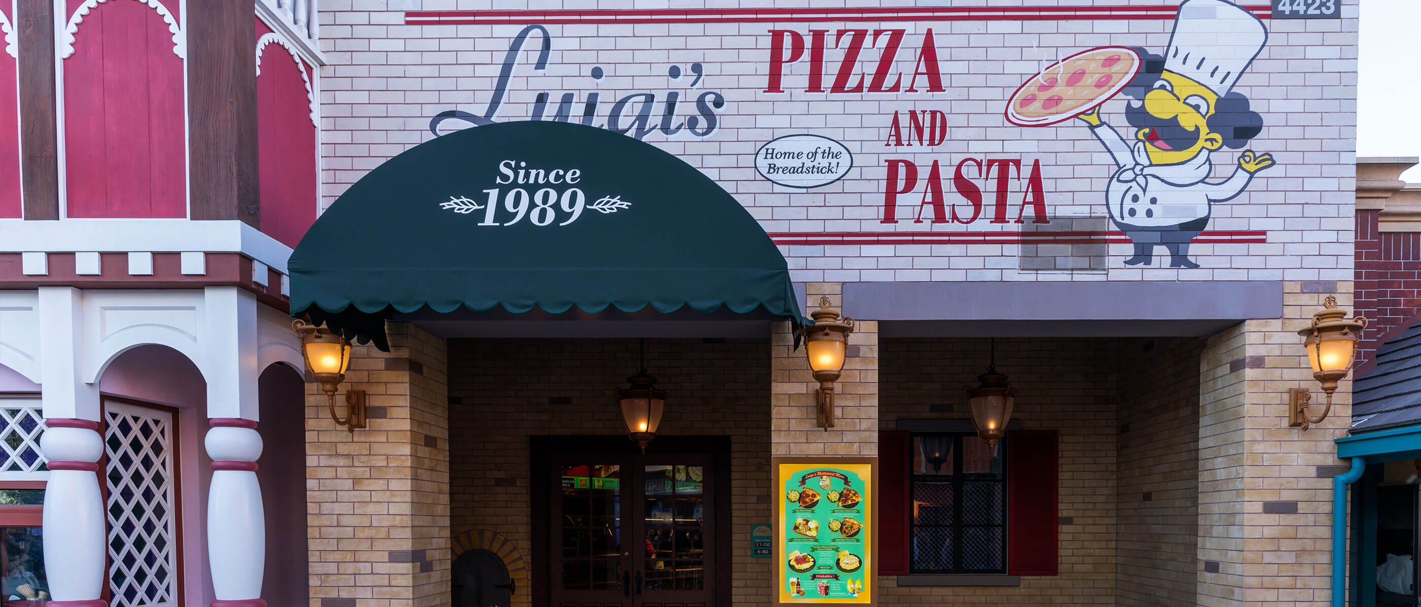 Luigi's Pizza and Pasta restaurant entrance with a little man holding a picture beside the sign.