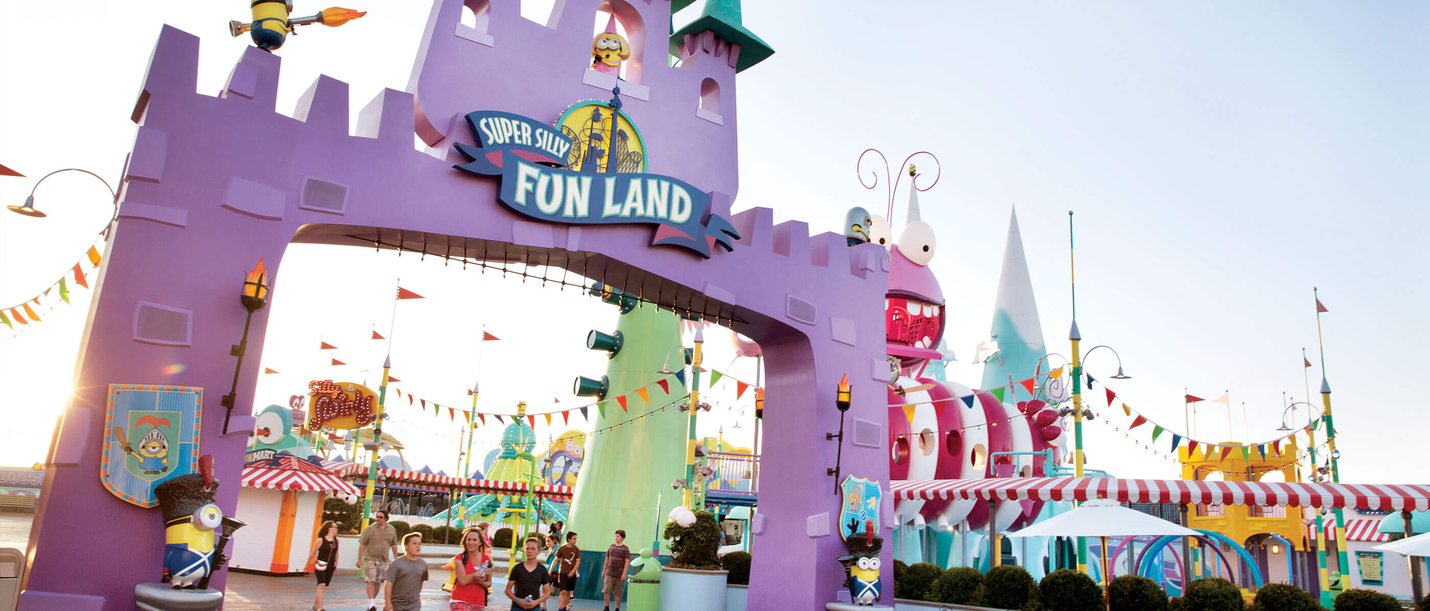 Purple archway entrance to Super Silly Fun Land with people walking.