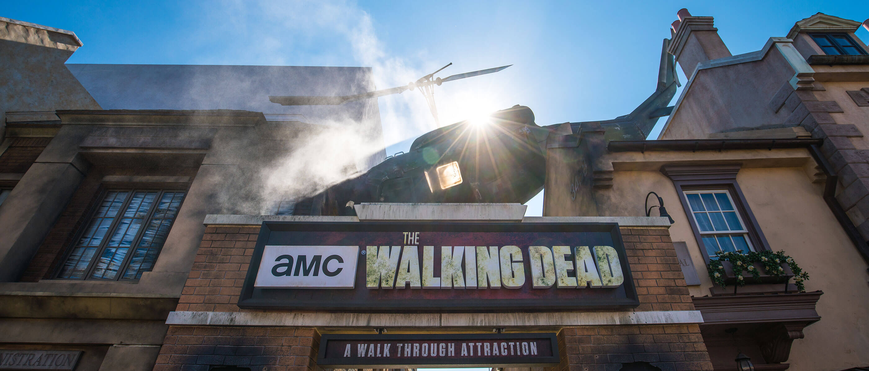 The sign for the Walking Dead Attraction with a broken down helicopter on top.