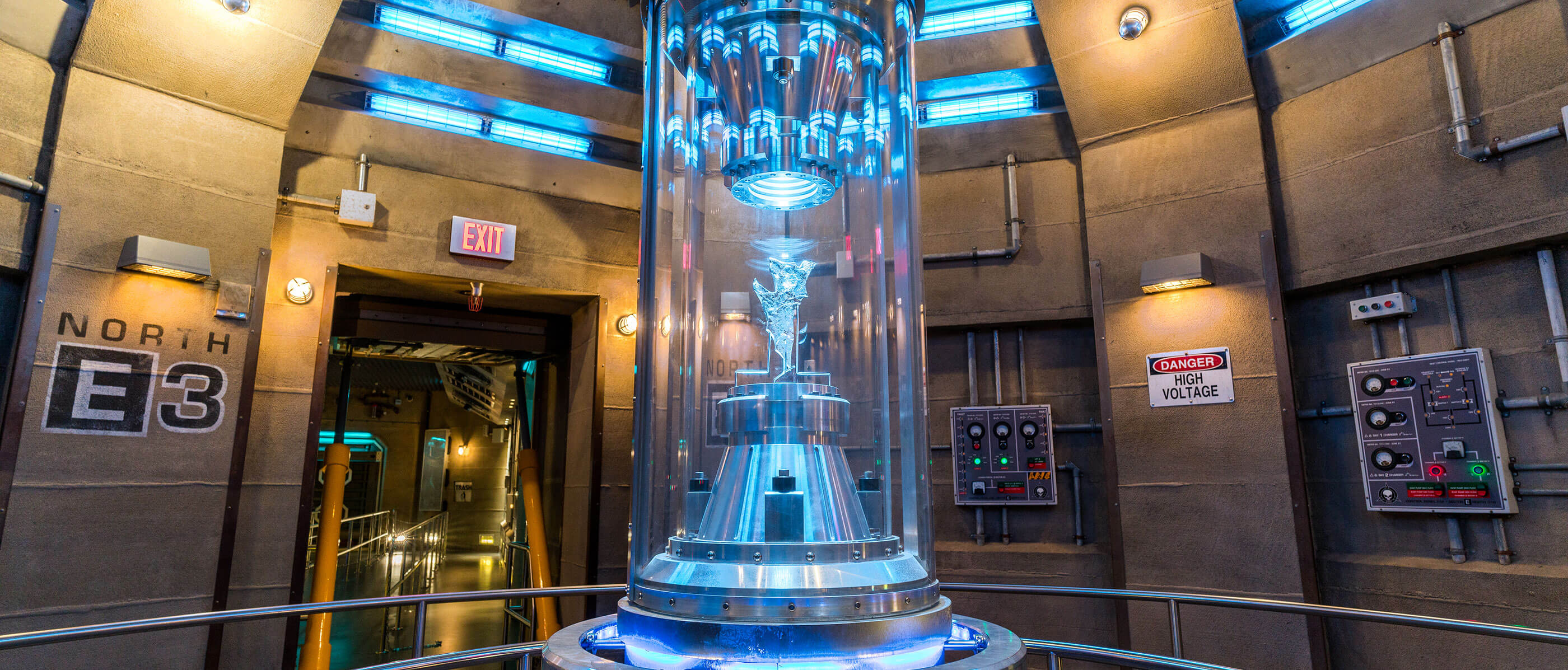 A stone room with a glass figure in a glass case that's place in the middle of the room.