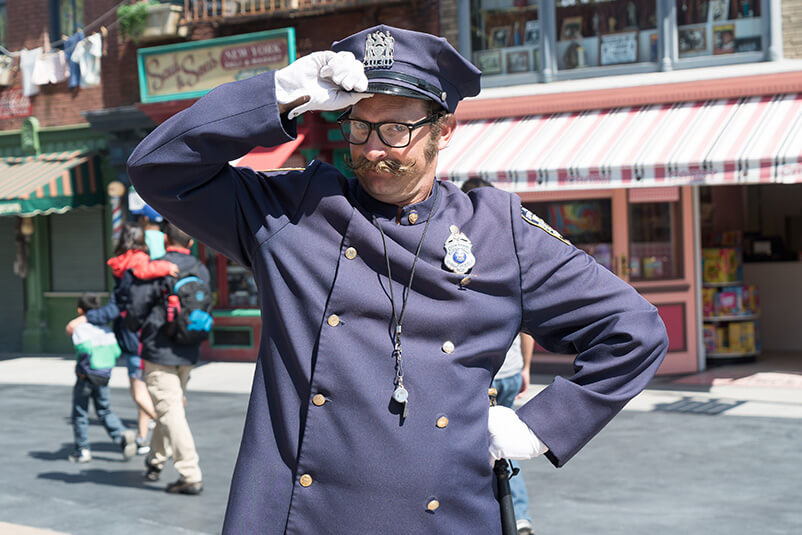 A police officer tipping his hat in front of a store.