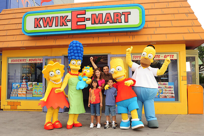 Family taking a picture with the Simpsons family in front of the Kwik-E-Mart entrance
