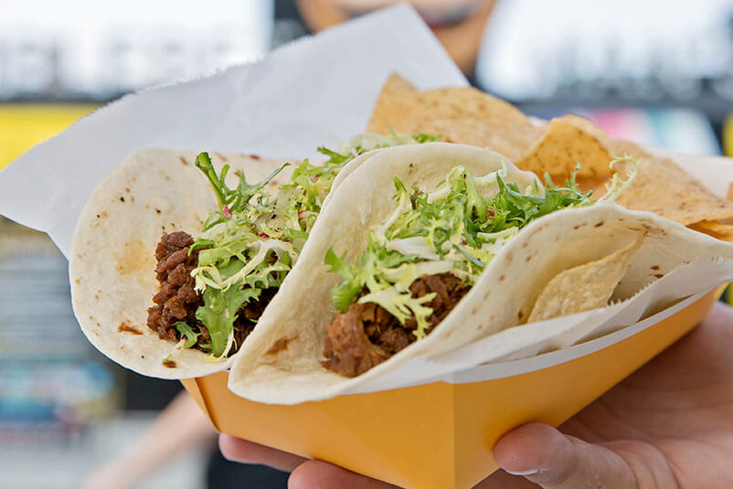 Two tacos with lettuce and meat on it.