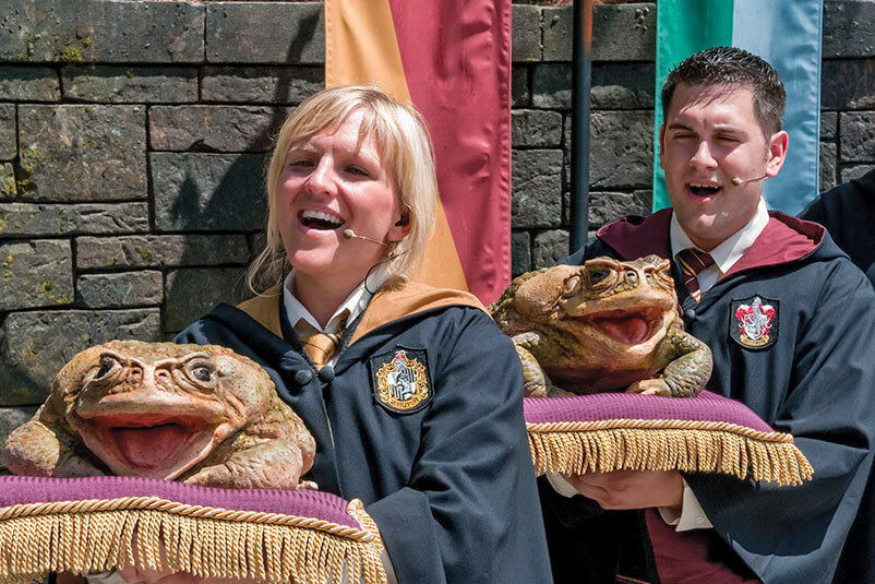 Two people singing with large frog props.