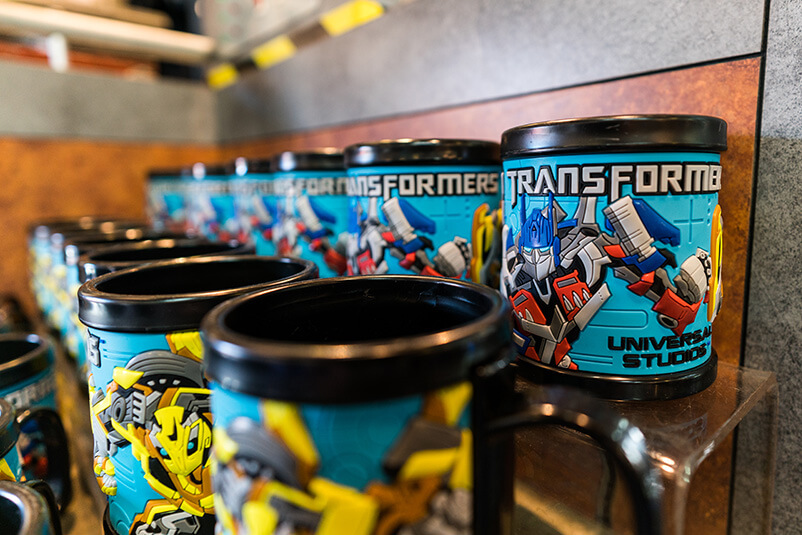 Rows of black mugs with Transformers on them.