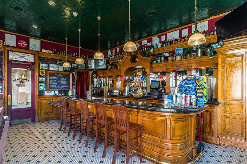 A bar with five stools and a checkered floor.