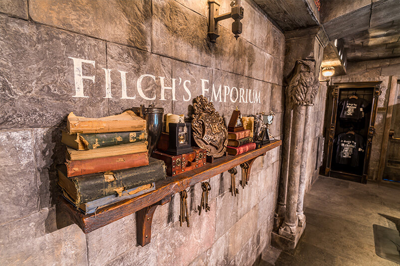 Wall with Filch's Emporium on it and a shelf with books.