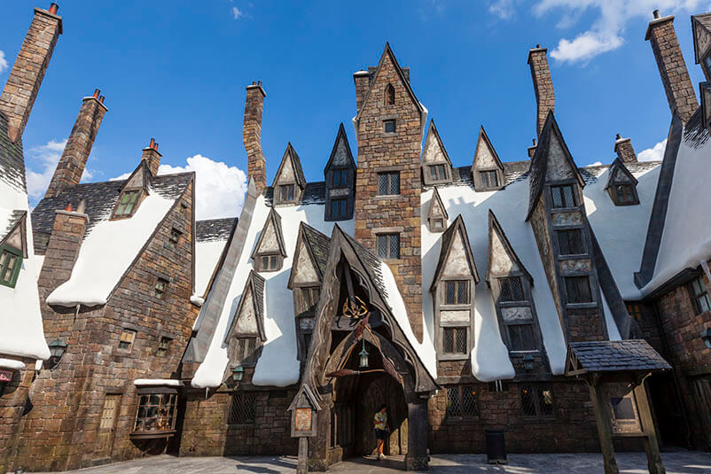 A stone house with multiple windows and with snow in the roof.
