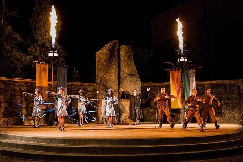 People performing on stage a scene from Harry Potter at night.