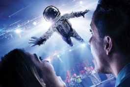 A man in a spacesuit floating towards a couple.