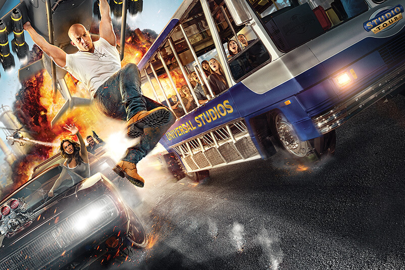 A Fast and the Furious poster with Vin Diesel holding onto a plan and a Universal Studio tour bus beside it.