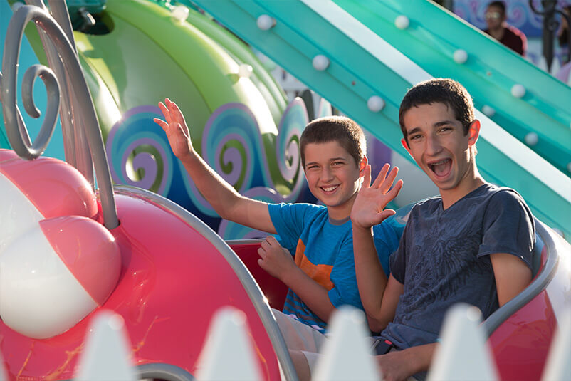 Two boys on a theme park ride in a pink cart.