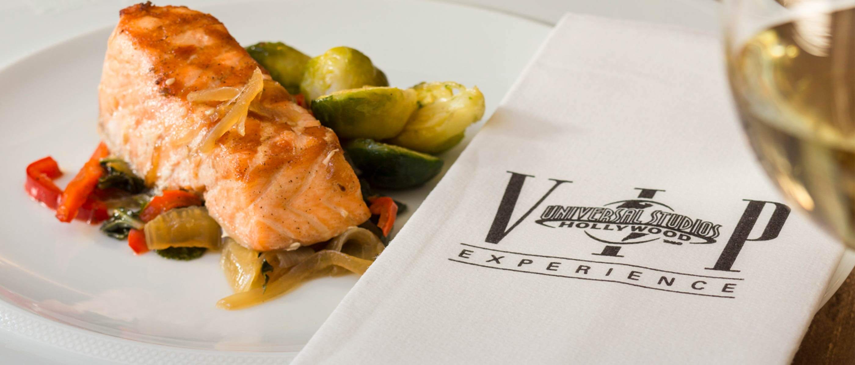 VIP Universal Studio Hollywood napkin with a plate of food beside it.
