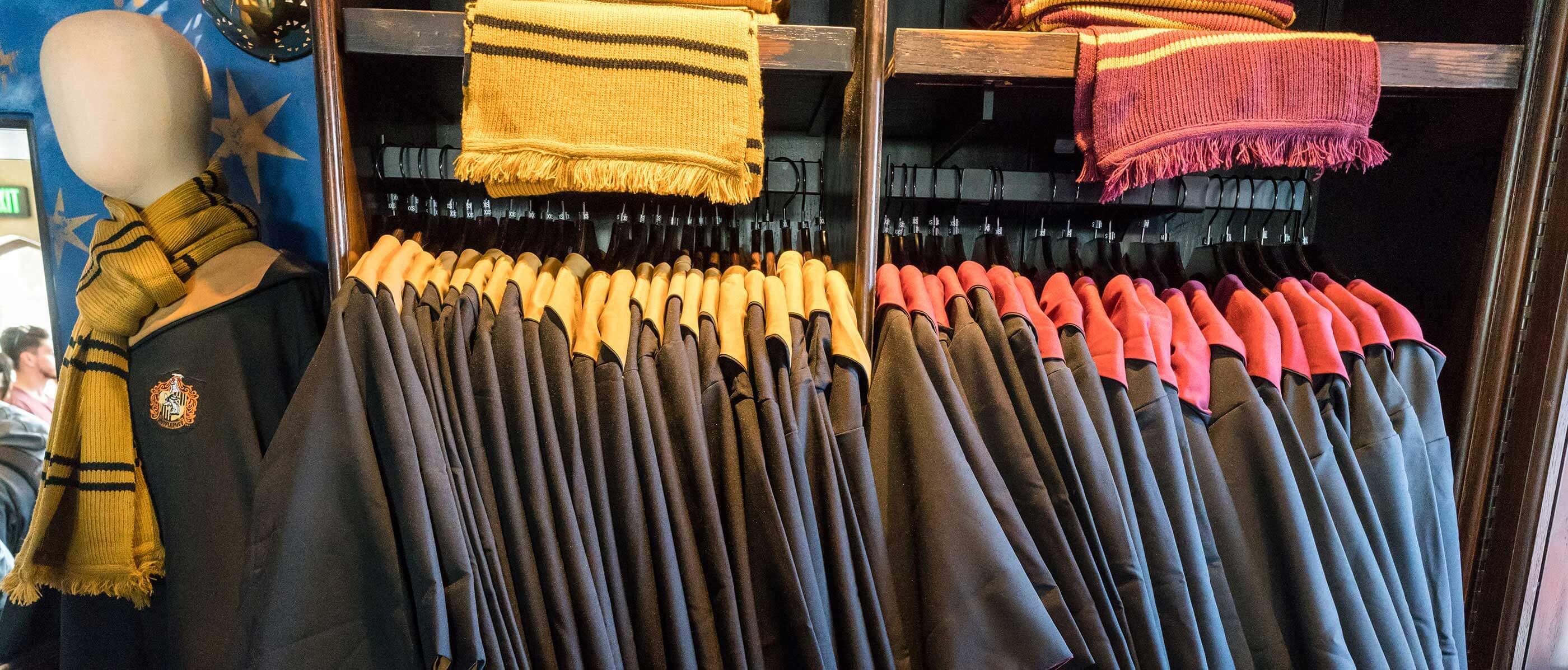 Multiple black wizard ropes hanging in a retail store with red and yellow scarfs on the shelf above.