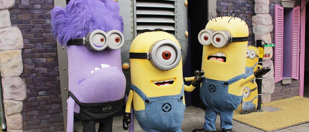 Two yellow Minions and a purple Minion in front of ride