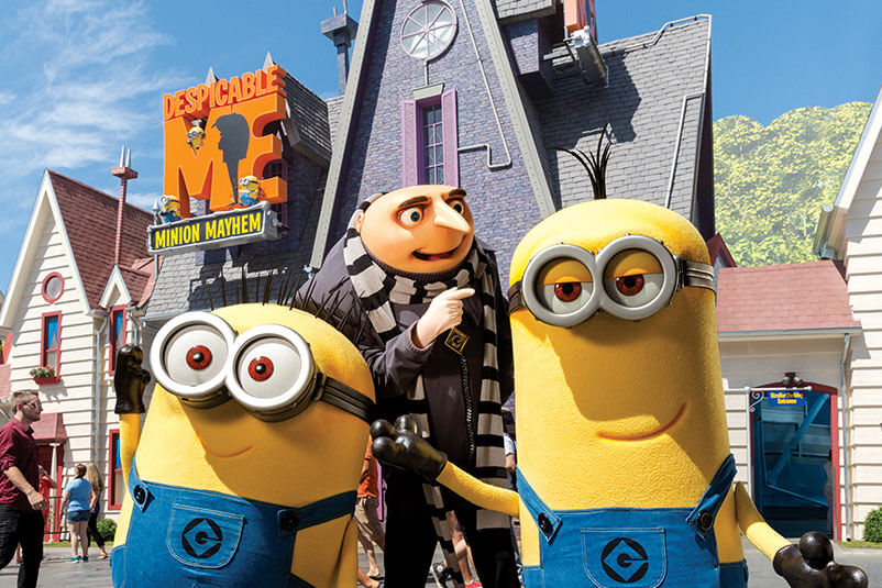 Gru and two minions in front of Gru's house.