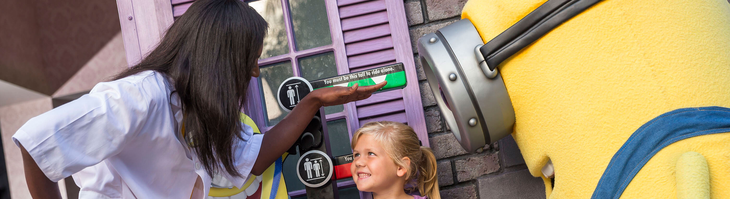 Employee checking to see if a child meets the height requirements for the minion ride.