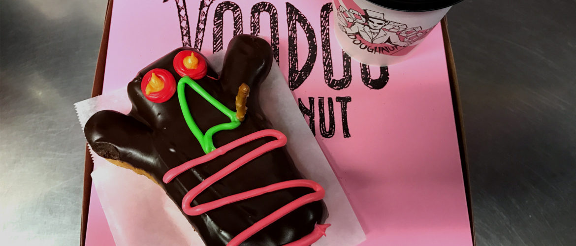 Voodoo Doughnut doll on top of a pink doughnut box